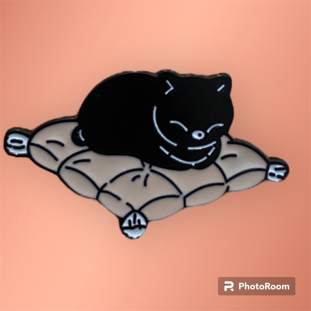 Black cat on a seat cushion enamel pin